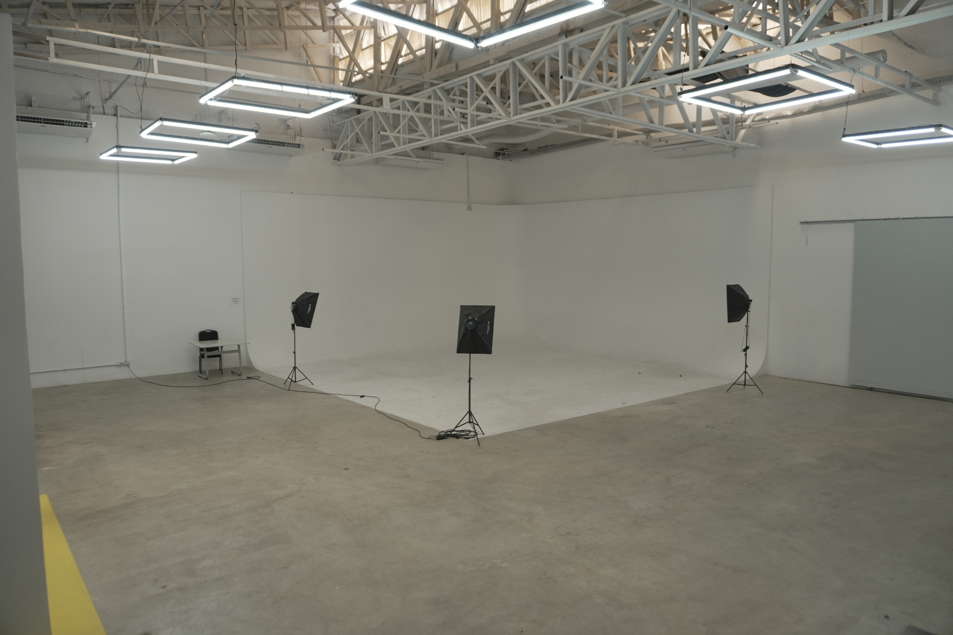Estúdio com fundo infinito branco e iluminação profissional para produções.